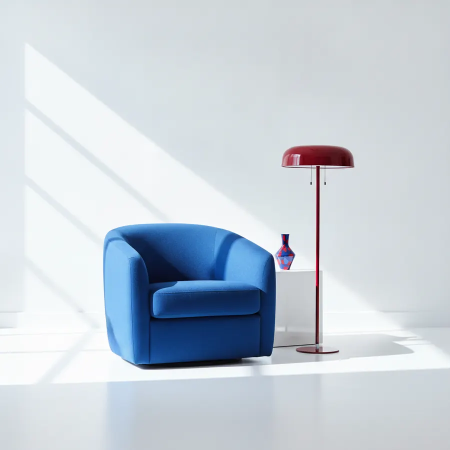 Un fauteuil club bleu vif, une lampe de sol a abat-jour rouge fonce sur pied rouge, et un petit vase bleu et rouge poses sur un cube blanc, le tout dans un espace aux murs et sol blancs