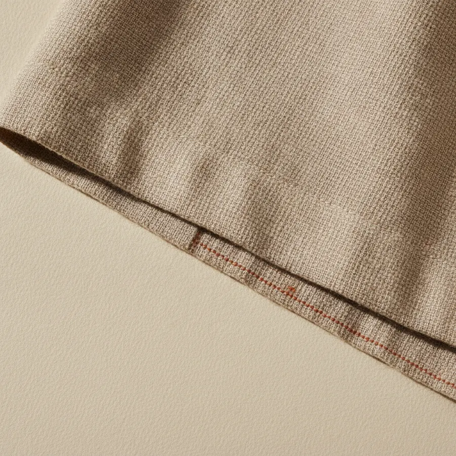 Un gros plan sur des coutures d ourlet et une lisiere de tissu de laine, la lumiere rasante montrant la densite du tissage