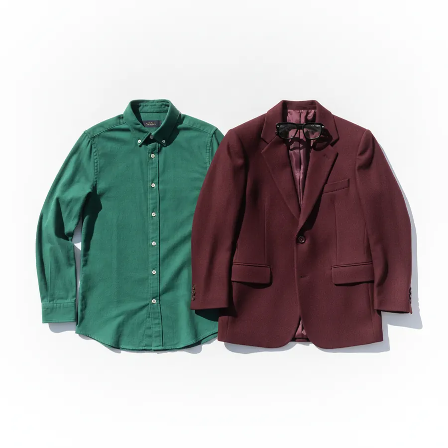 Une chemise verte et une veste bordeaux posees a plat cote a cote sur fond blanc, avec une paire de lunettes a monture epaisse posee dessus
