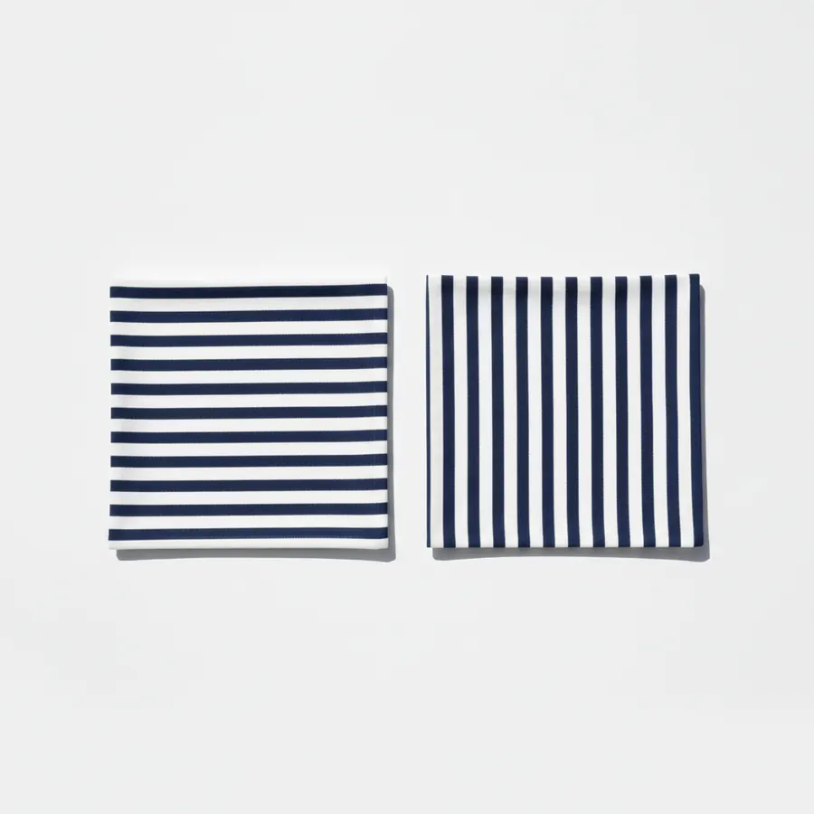 Deux carrés de tissu identiques posés côte à côte sur un fond blanc, l'un rayé horizontalement, l'autre rayé verticalement, tous deux en bleu marine et blanc, photographiés de face en lumière égale