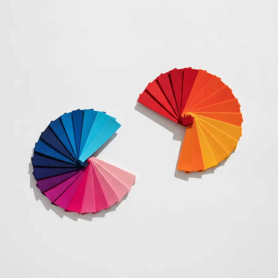 Deux eventails de petits rectangles de papier colores poses sur un fond gris clair : l'un a gauche regroupe des teintes froides allant du bleu marine au rose et violet, l'autre a droite regroupe des teintes chaudes allant du rouge au orange et jaune